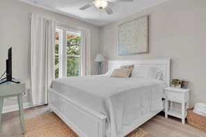 A bedroom with a bed, a nightstand, a lamp, a television, and a window with curtains. - 3 Ensuites, Dogs OK, Hot Tub! (Emerald Isle)
