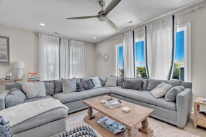A modern living room with a grey sectional sofa, a wooden coffee table, and a ceiling fan. - 3 Ensuites, Dogs OK, Hot Tub! (Emerald Isle)