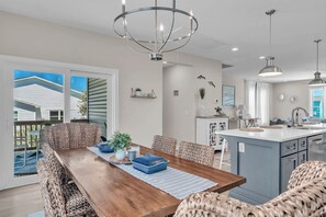 A dining area with a wooden table, wicker chairs, and a chandelier. - 3 Ensuites, Dogs OK, Hot Tub! (Emerald Isle)