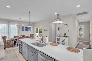 A modern kitchen with a large island, pendant lights, and a dining area with wicker chairs. - 3 Ensuites, Dogs OK, Hot Tub! (Emerald Isle)