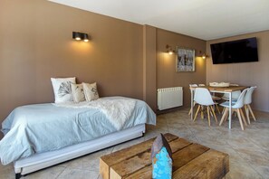 Un dormitorio con cama, mesita de noche y televisor montado en la pared.