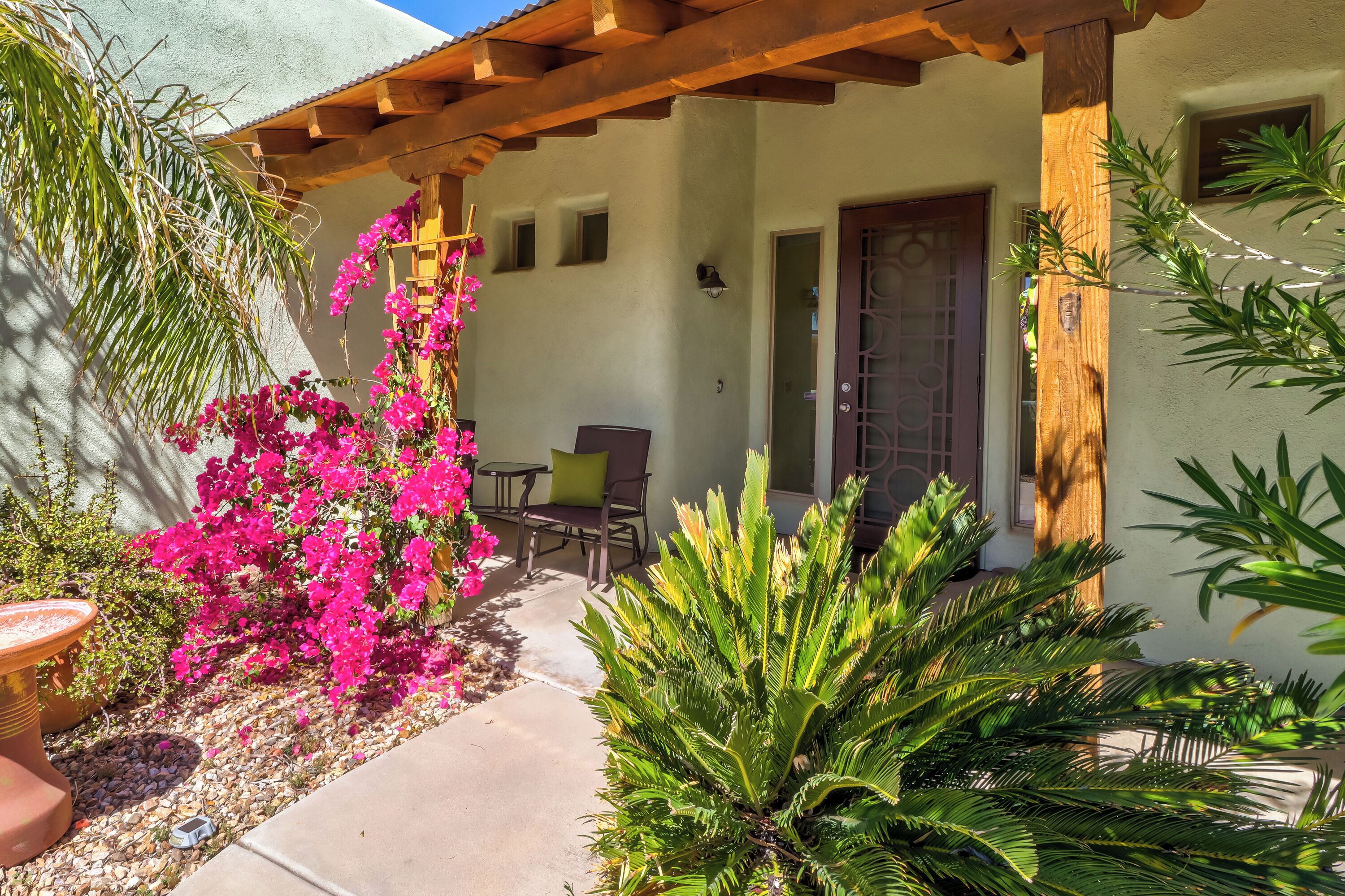 A patio with a pergola, a seating area, and a door.