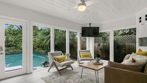 A sunlit room with a pool, white walls, and a ceiling fan. - Pool Home Oasis - Home for five (Tampa)