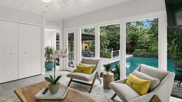 A modern living room with a pool view, white walls, and a ceiling fan. - Pool Home Oasis - Home for five (Tampa)