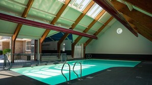 Ein Hallenbad mit Oberlichter, einem sichtbaren Wasserfiltersystem und einem Schild mit der Aufschrift 'NATERPRET'.