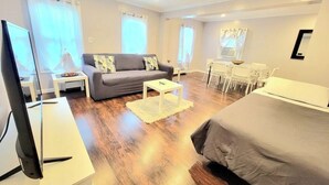 Una habitación de hotel moderna con sofá, cama, televisor, escritorio y una silla.