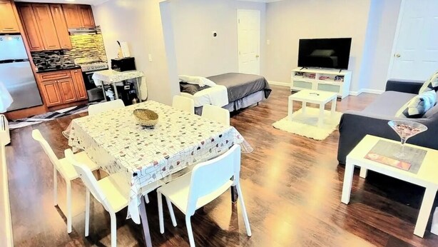 Un espacio habitable compacto con kitchenette, comedor, sofá, televisor y una pequeña mesa.