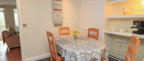 Un coin repas avec une table dressée pour quatre personnes, une machine à café et un panneau mural affichant des messages positifs.