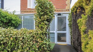 Ein Wohnhaus mit Backsteinfassade, einer weißen Tür und einem kleinen Garten mit einem Kiesweg, der zur Tür führt.