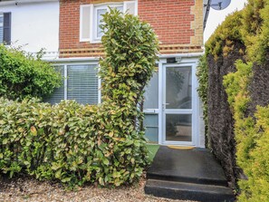 A residential property with a brick facade, a white door, and a small garden area with a gravel path leading to the door. - Bosun's Deck (Christchurch)