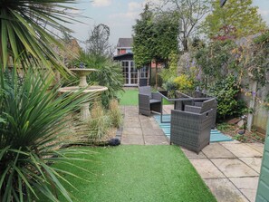 A garden with a patio area, a fountain, and outdoor furniture. - Bosun's Deck (Christchurch)