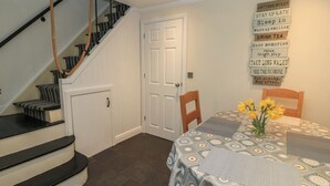 Eine Treppe mit schwarz-weißen Mustern, eine weiße Tür und ein Tisch mit einer gemusterten Tischdecke und gelben Blumen.