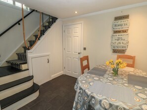 A staircase with black and white patterned steps, a white door, and a table with a patterned tablecloth and yellow flowers. - Bosun's Deck (Christchurch)