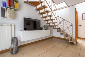 A modern living room with a built-in TV, a white console, a geometric staircase, and a bookshelf with books. - [Porta Venezia] Cozy and comfortable loft (Milan)
