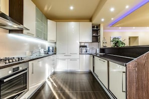 Une cuisine moderne dotée d’appareils électroménagers en acier inoxydable, de meubles blancs et d’un mur d’accent en bois foncé.