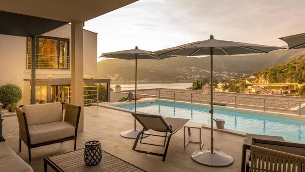 A rooftop pool area with lounge chairs, umbrellas, and a view of the surrounding landscape. - Luxury Five Bedroom Villa With Pool (Zaton)