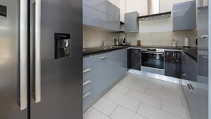 A modern kitchen with stainless steel appliances, grey cabinetry, and a tiled backsplash. - Luxury Five Bedroom Villa With Pool (Zaton)