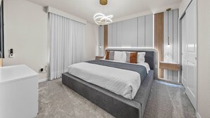 A modern bedroom with a large bed, a bedside table, a wardrobe, and a ceiling light fixture. - 10BR house at Windsor Cay Resort (Clermont)