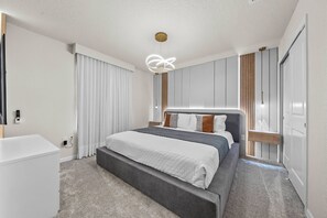 Ein modernes Schlafzimmer mit einem großen Bett, einem Nachttisch, einem Kleiderschrank und einer Deckenleuchte.