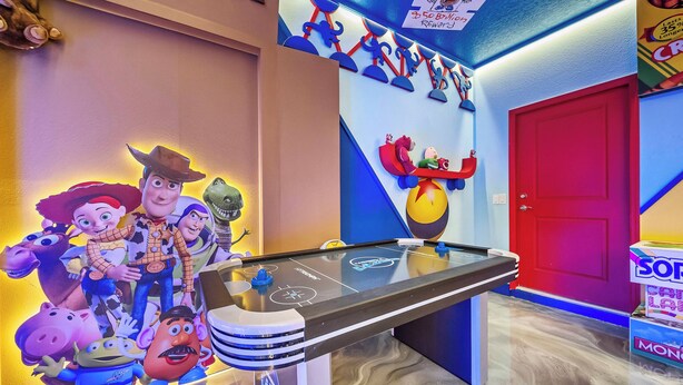 A room with a pool table, a red door, and a wall with cartoon character decorations. - 10BR house at Windsor Cay Resort (Clermont)