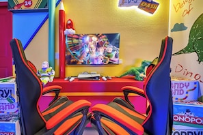 Ein Gaming-Einrichtung mit Fernseher, Spielkonsole und weichen Kuscheltieren.