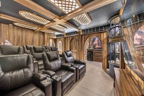 Une salle de cinéma privée avec des fauteuils en cuir inclinables, des panneaux de bois et un grand écran.