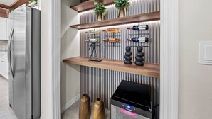 A kitchen with a built-in oven, a stainless steel refrigerator, and a wooden shelf with decorative items. - 10BR house at Windsor Cay Resort (Clermont)