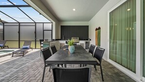 A modern outdoor dining area with a table, chairs, and a decorative pineapple centerpiece. - 10BR house at Windsor Cay Resort (Clermont)