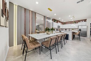 Une cuisine moderne dotée d’un îlot central, de meubles blancs et d’appareils électroménagers en acier inoxydable.