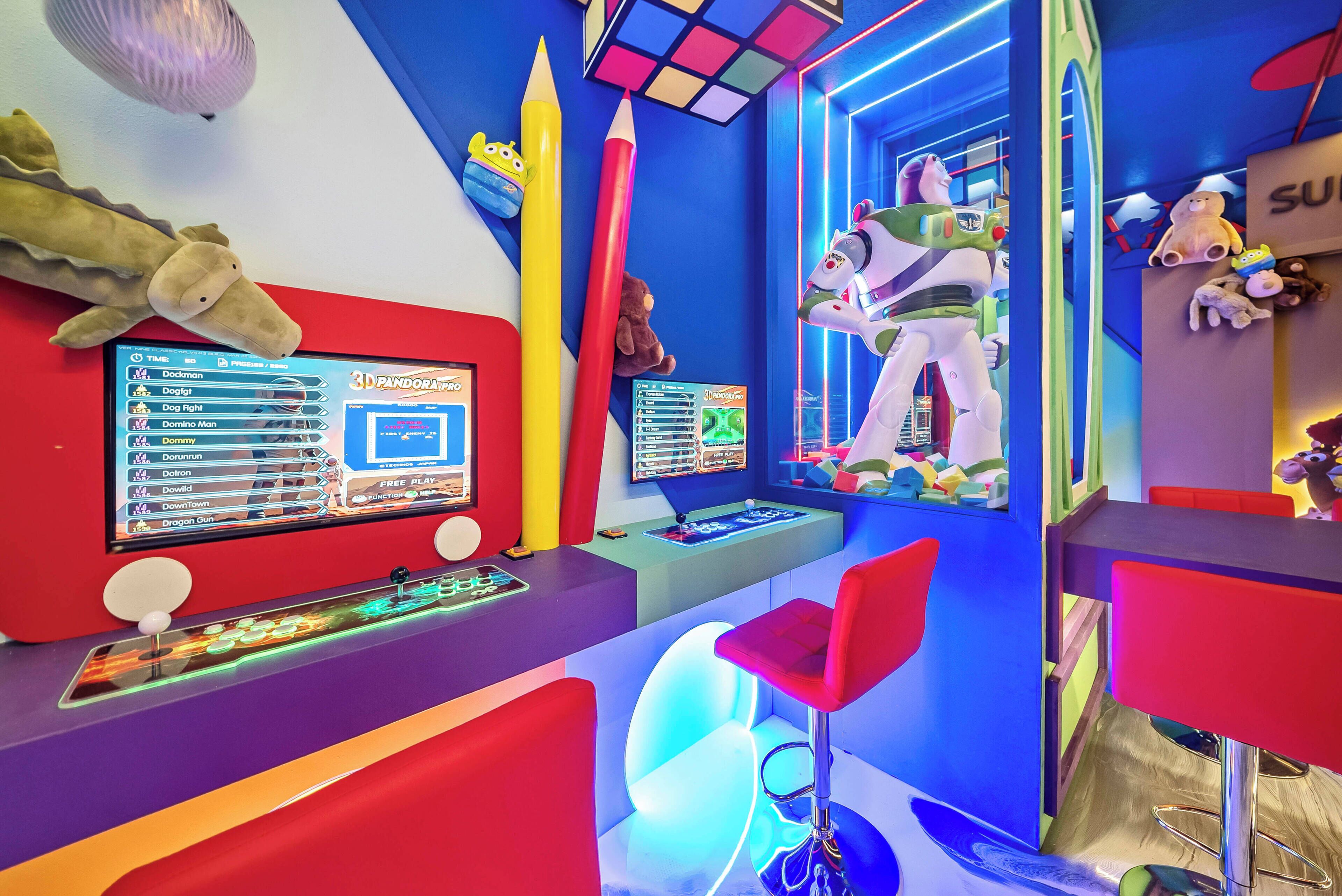 Una habitación colorida con una consola de videojuegos 3D, peluches y una figura de juguete grande.