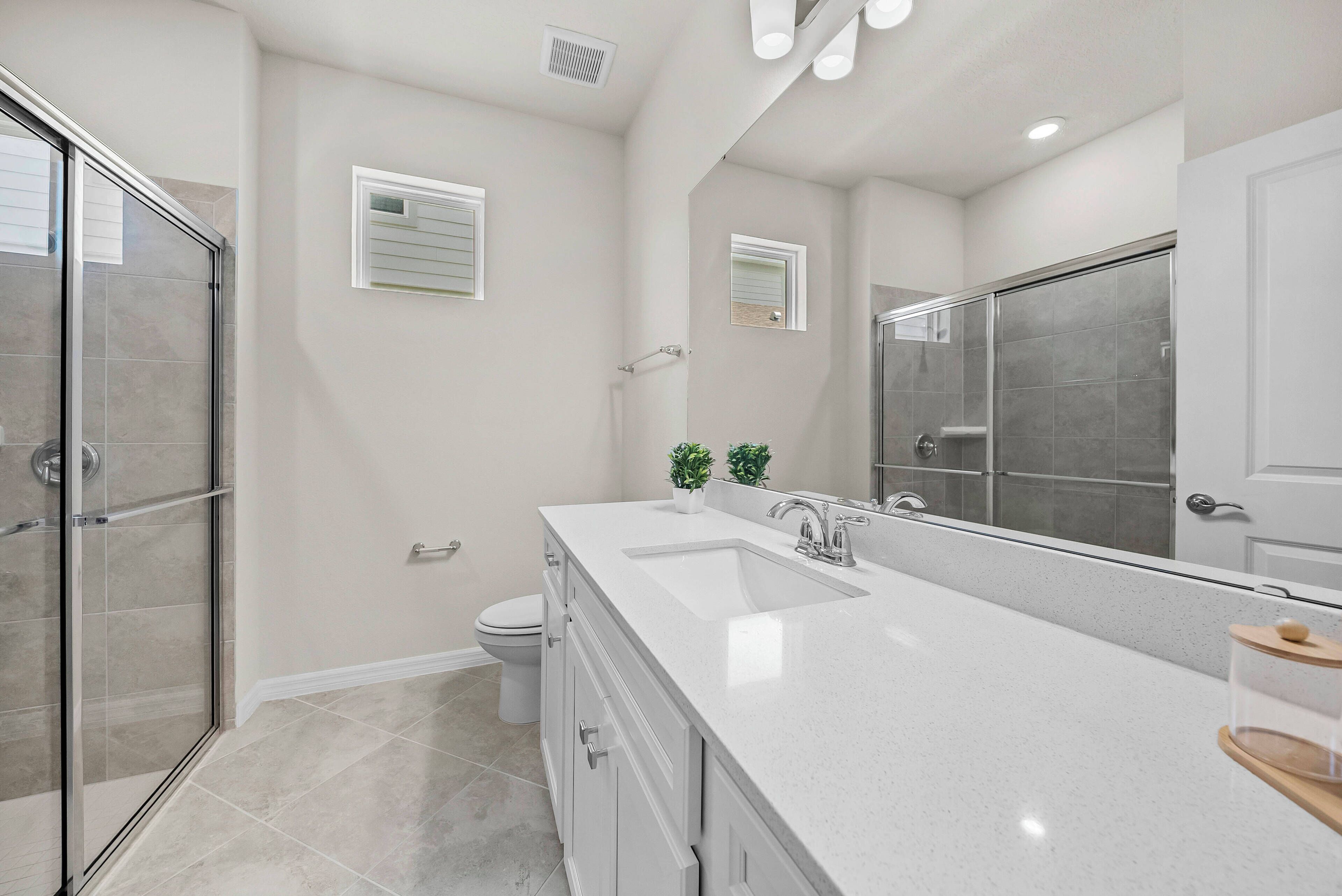 A modern bathroom with a glass shower enclosure, a large vanity with a double sink, and a large mirror.