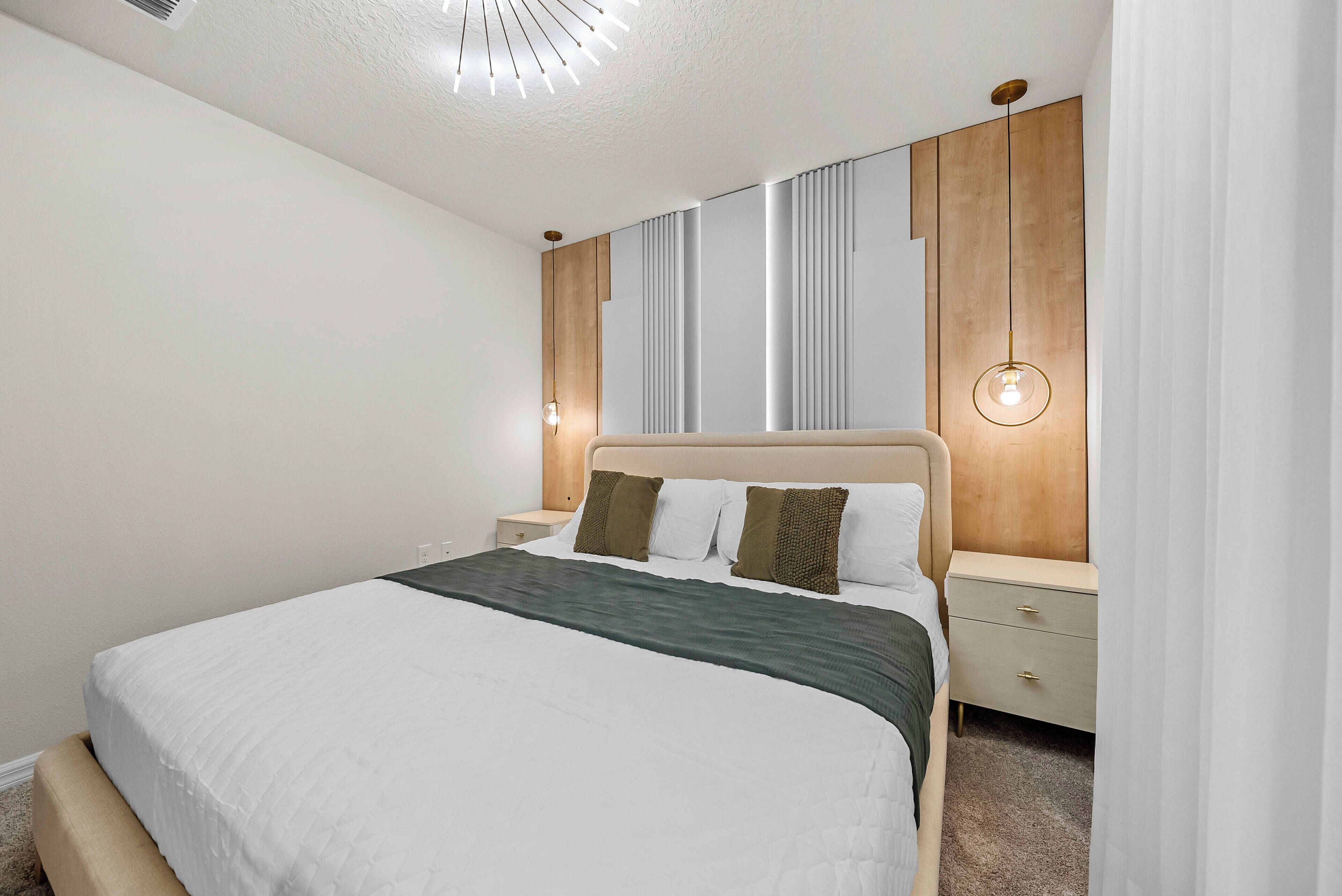 Une chambre moderne avec un grand lit, des tables de chevet et un luminaire fixé au mur.