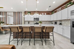 A modern kitchen with a central island, bar stools, and a dining area with a table and chairs.
