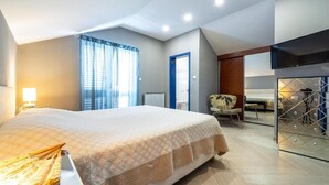Ein modernes Hotelzimmer mit einem großen Bett, einem Schreibtisch, einem Sessel und Blick auf die Stadt.