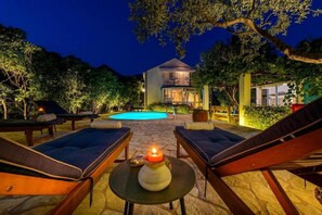 A poolside area with lounge chairs, a candle, and a building in the background. - Family Four Bedroom Holiday Home with Pool (Mlini)
