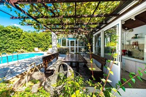 A covered outdoor seating area with a pool, a wooden table, and wicker furniture. - Family Four Bedroom Holiday Home with Pool (Mlini)