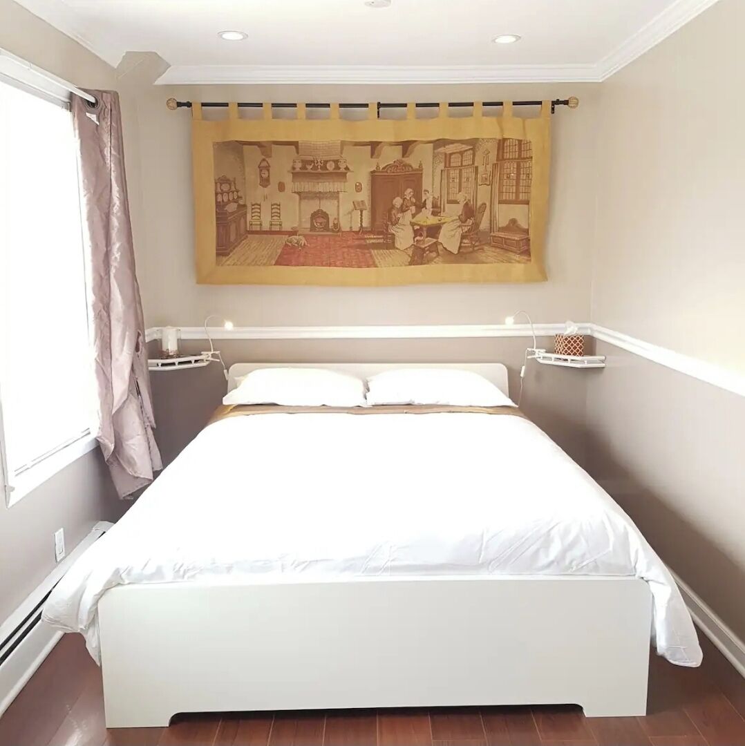 Une chambre à coucher avec un lit, des rideaux, une tapisserie murale et une table de chevet.