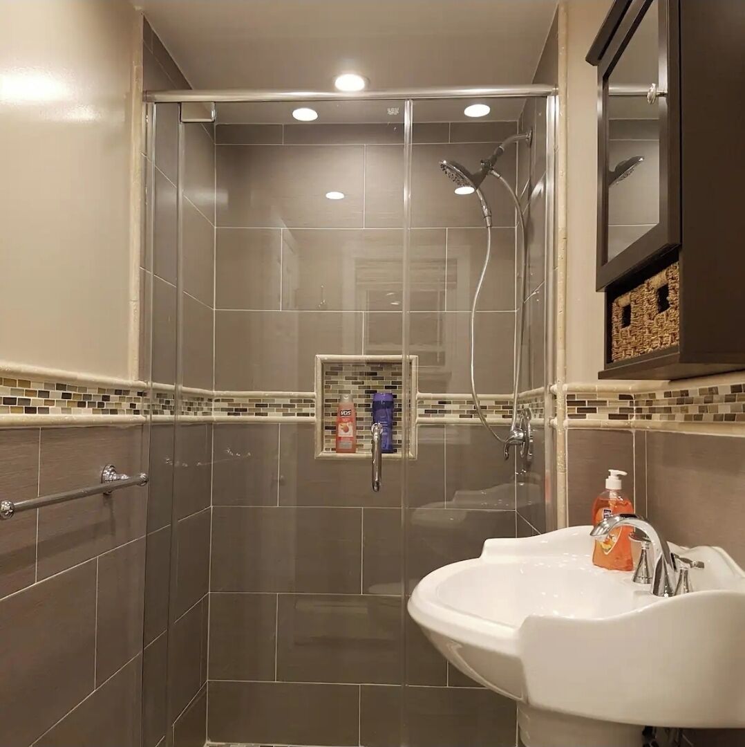 A modern bathroom with a glass-enclosed shower, a white sink, and a mirror cabinet.