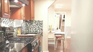 A kitchen with a gas stove, oven, and microwave, wooden cabinets, and a tiled backsplash.