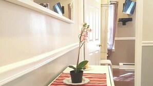 A hallway with a potted orchid, a glass of red drink, and a striped rug on a white table.