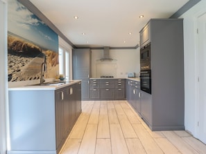 A modern kitchen with grey cabinets, a built-in oven, and a large window.