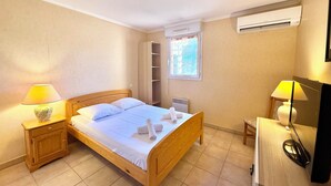 Une chambre à coucher avec un lit en bois, deux lampes de chevet, une armoire, un appareil de climatisation et une fenêtre donnant sur un beau paysage.