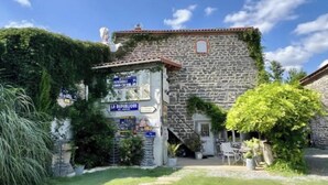 A stone building with ivy, a sign for 'LA REPUBLIQUE,' and outdoor seating. - Les Hirondelles du Marais (Riom)