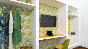 Een kamer met een bed, een bureau met een laptop, een stoel, een televisie en een kledingkast.
