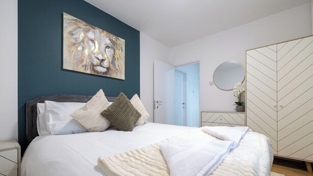 A bedroom with a bed, pillows, a painting, a wardrobe, and a mirror. - The Hove Retreat | Sleeps 10 | 4BR Coastal Escape (Brighton and Hove)