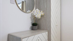 A bathroom vanity with a mirror, a potted orchid, and a herringbone-patterned wall. - The Hove Retreat | Sleeps 10 | 4BR Coastal Escape (Brighton and Hove)