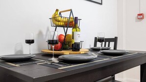 A dining table with plates, cutlery, a fruit basket, wine glasses, and a bottle. - The Hove Retreat | Sleeps 10 | 4BR Coastal Escape (Brighton and Hove)