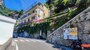 A narrow street with a stone wall on one side and a building with balconies. - YourHome - Casa Giulia (Positano)