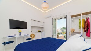 A modern hotel room with a bed, a desk, a TV, and a balcony with a view. - YourHome - Casa Giulia (Positano)