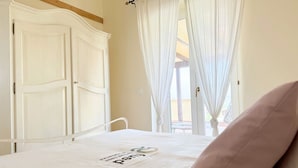 Een slaapkamer met een bed, een kledingkast en een raam met gordijnen.